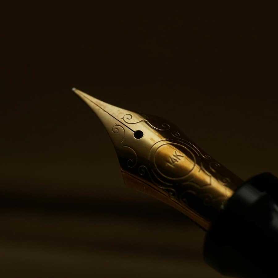 Close-up of a gold fountain pen nib in warm low light