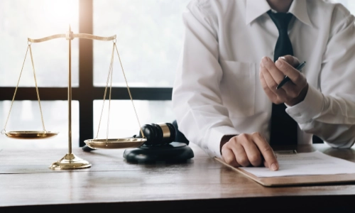 Male lawyer sitting in his desk is reviewing a contract's details.