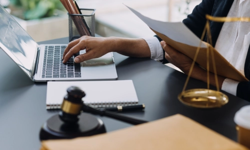 A lawyer reviewing a case and typing on his laptop.