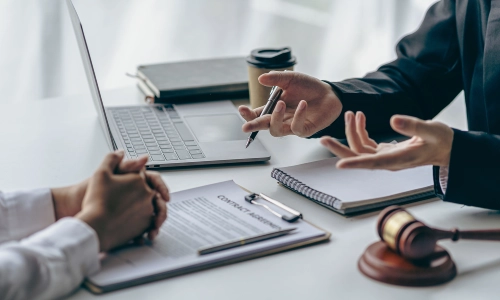 A lawyer holding a pen discussing a case with another lawyer who has his hands clasped together