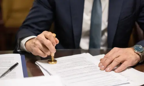 A man in a suit stamping a seal on a document.