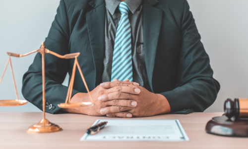 An Albany business lawyer sitting behind his desk with fingers clasped.