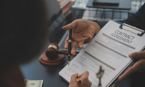 Albany landlord tenant lawyer reviewing a contract with a client in the office, holding a pen while discussing legal matters face to face.