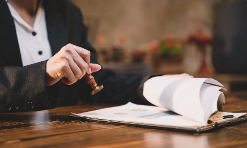 An Albany M&A lawyer placing a stamp on a legal document at an office desk.