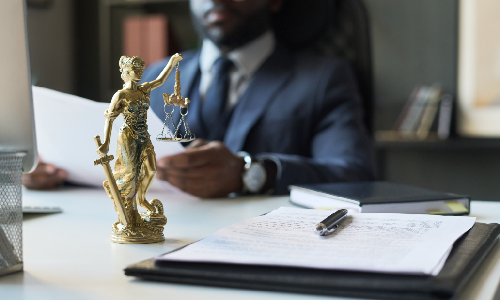 Albany small business lawyer sitting at his desk with a statue of "Lady Justice," reviewing a business document.