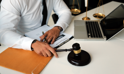 New York breach of contract lawyer holding a hammer on a gavel with his other hand on a contract on an office table.