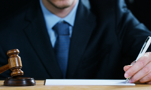  Close up of a New York business formation lawyer signing documents on his work table in the office.