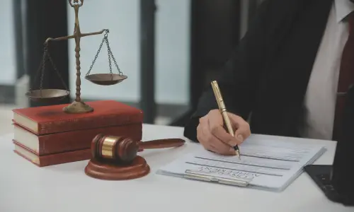 A New York contract dispute lawyer reviewing the details of a contract agreement laid out on the table beside a "scales of justice" and a hammer and gavel.