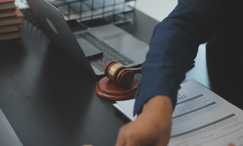Close up of a New York M&A Lawyer organizing files on a table with a laptop.