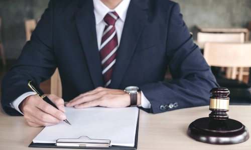 A New York Personal Injury Lawyer signing a document with a black pen in his office