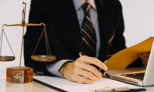 A New York residential real estate lawyer working on his laptop while consulting notes.