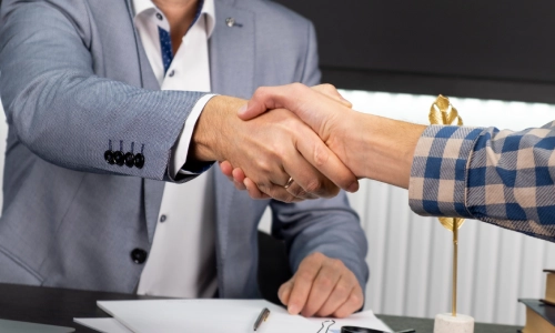 Client shaking hands with an Albany personal injury lawyer across a table with documents and a pen.