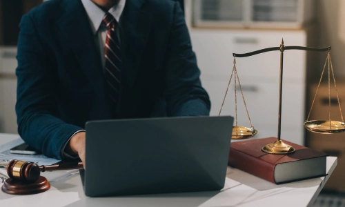 A business formation lawyer is working on a black laptop while they sit in a Glens Falls law office